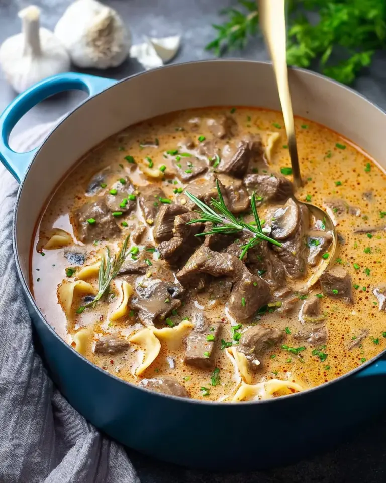 Bowl of creamy beef stroganoff soup with vegetables and herbs