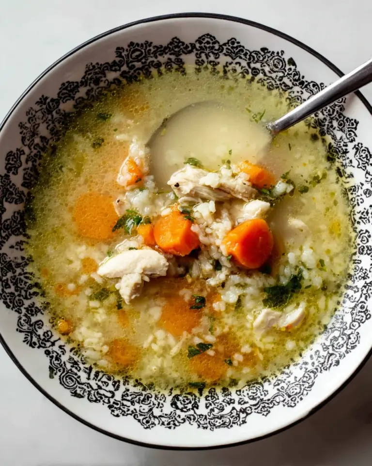 Bowl of turkey rice soup with vegetables and herbs, a comforting meal.