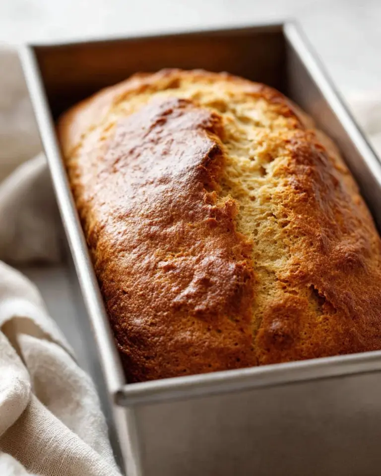 Loaf of freshly baked banana bread with slices on a wooden table