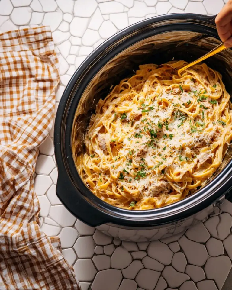 Delicious Crockpot Chicken Alfredo served with pasta and garnish