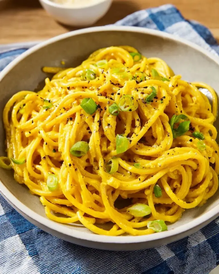 Plate of flavorful garlic noodles garnished with green onions and sesame seeds.