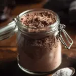 A large jar of homemade hot cocoa mix ready for winter drinks