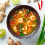 Bowl of Tom Yum Goong, a spicy Thai shrimp soup with fresh herbs and lime.