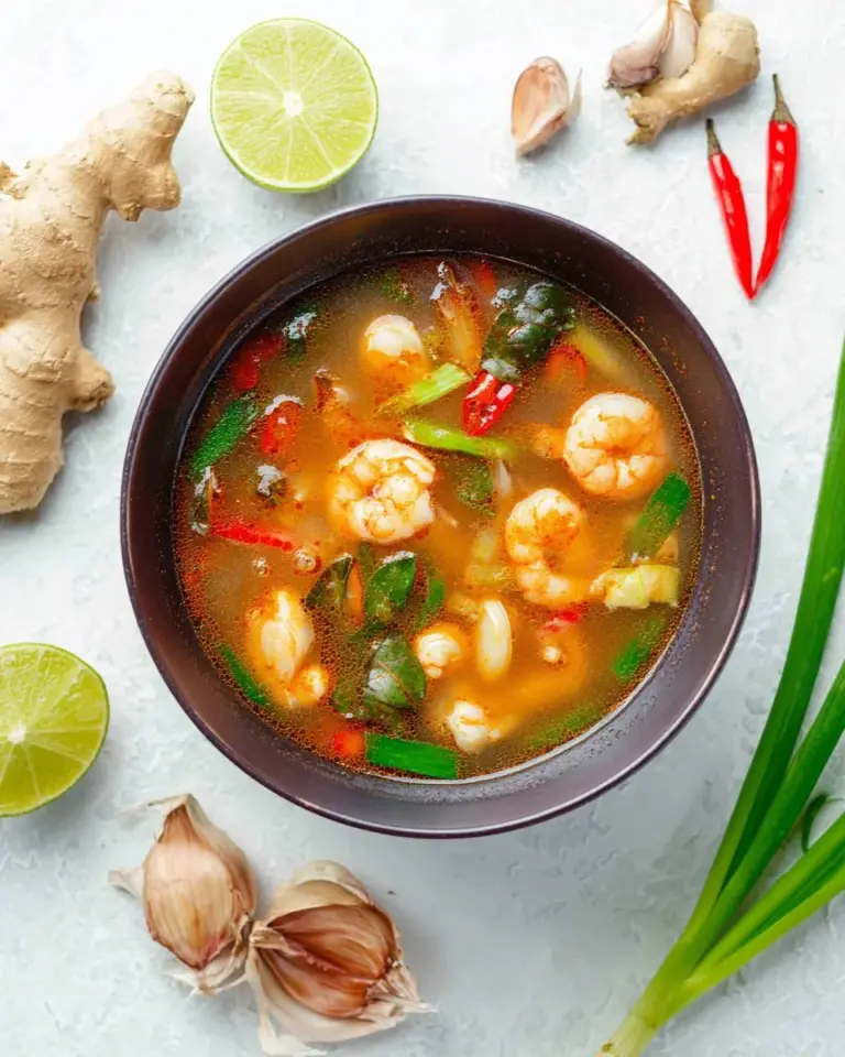 Bowl of Tom Yum Goong, a spicy Thai shrimp soup with fresh herbs and lime.