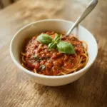 Homemade spaghetti sauce in a rustic bowl with fresh herbs.